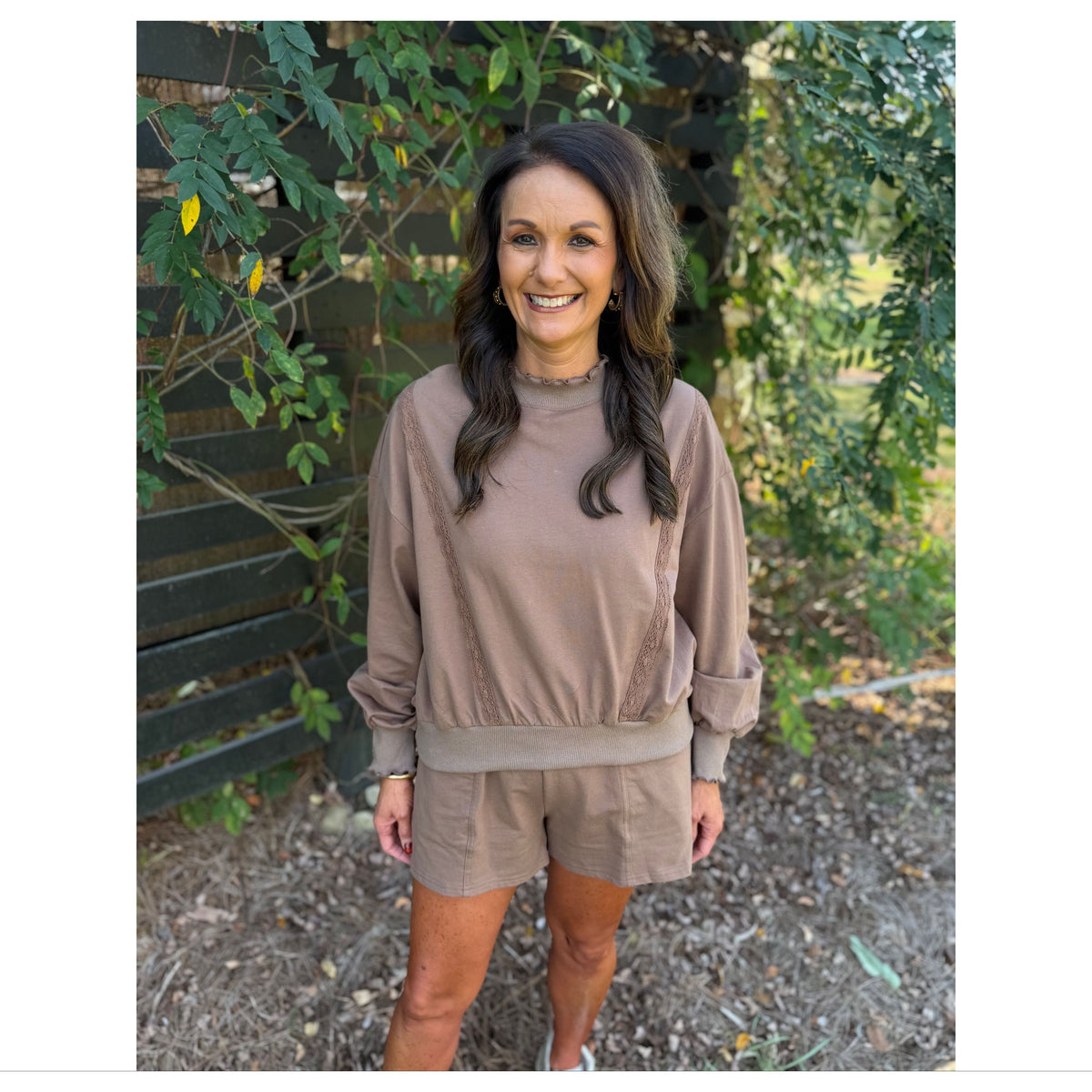 Annie Ks Boutique mocha lounge set with a cropped sweatshirt featuring lace trim and matching shorts in a garden.