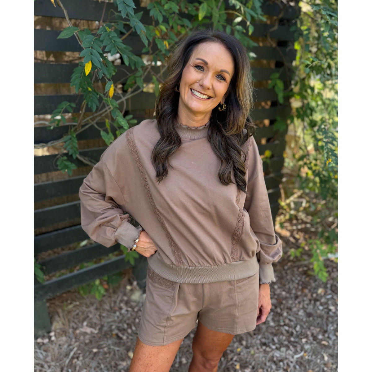 Annie Ks Boutique mocha lounge set with a cropped lace-trim sweatshirt and matching shorts on a smiling woman.