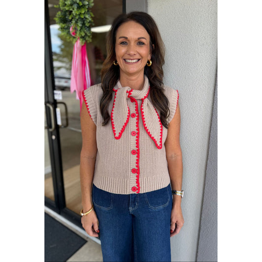 Annie Ks Boutique mocha sweater vest with red blanket stitching, tie neck, and button front worn by a smiling woman.