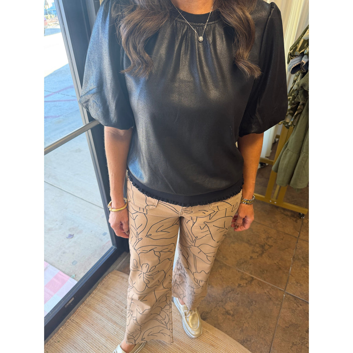 Annie Ks Boutique monochrome floral print wide-leg jeans paired with a black puff-sleeve top in a retail setting.