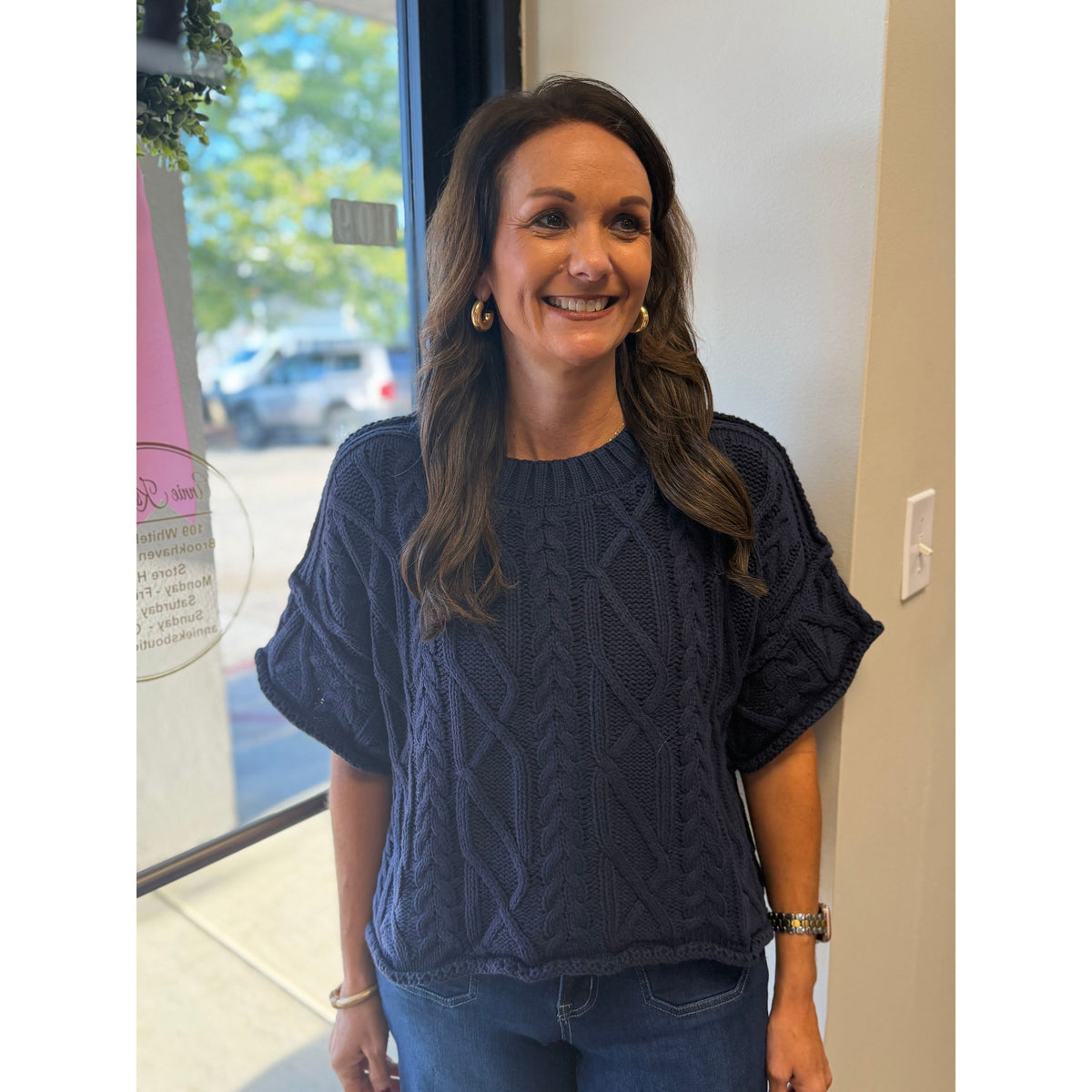 Annie Ks Boutique navy cropped cable knit sweater with short sleeves and a round neckline worn by a smiling woman