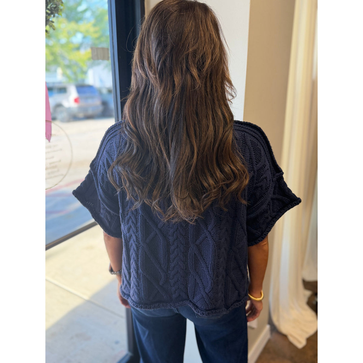 Annie Ks Boutique navy blue cropped knit sweater with cable knit texture worn by a woman from the back view