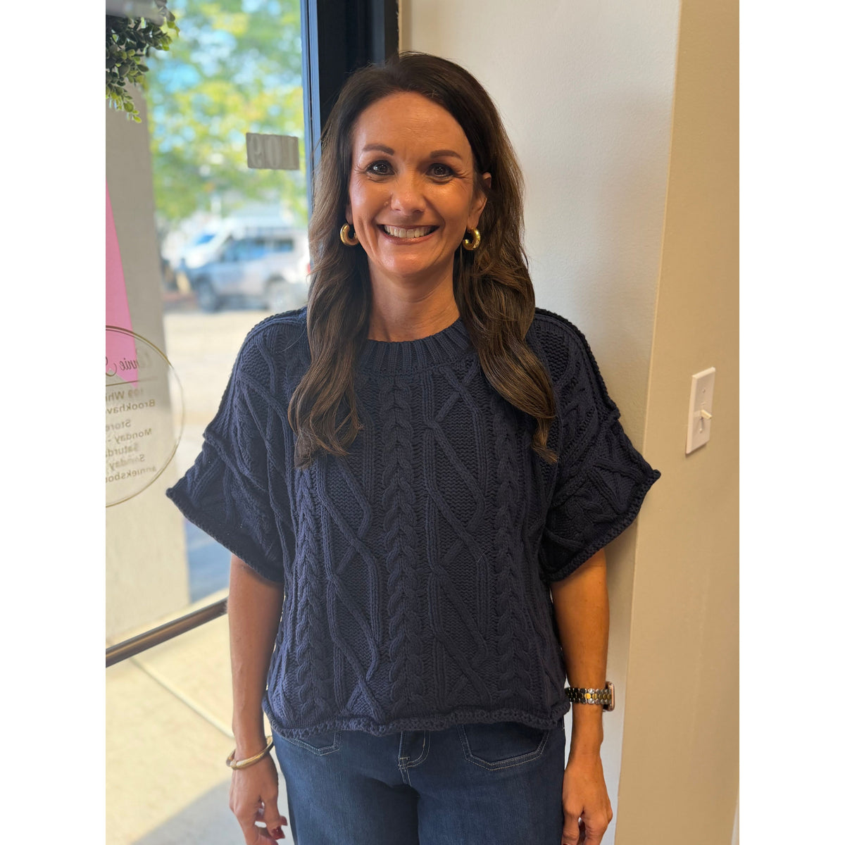 Annie Ks Boutique navy blue cropped knit sweater with cable knit texture and round neckline worn by a smiling woman