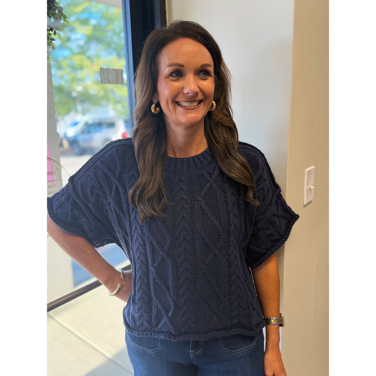 Annie Ks Boutique navy blue cropped cable knit sweater with a round neckline worn by a smiling woman