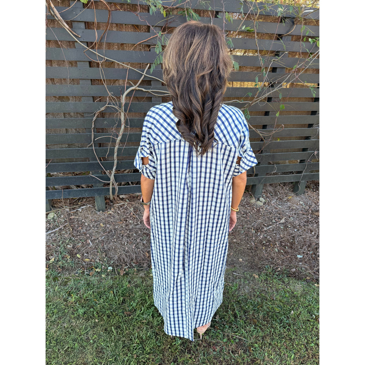 Back view of a woman wearing an Annie Ks Boutique navy and white gingham midi dress with short sleeves.