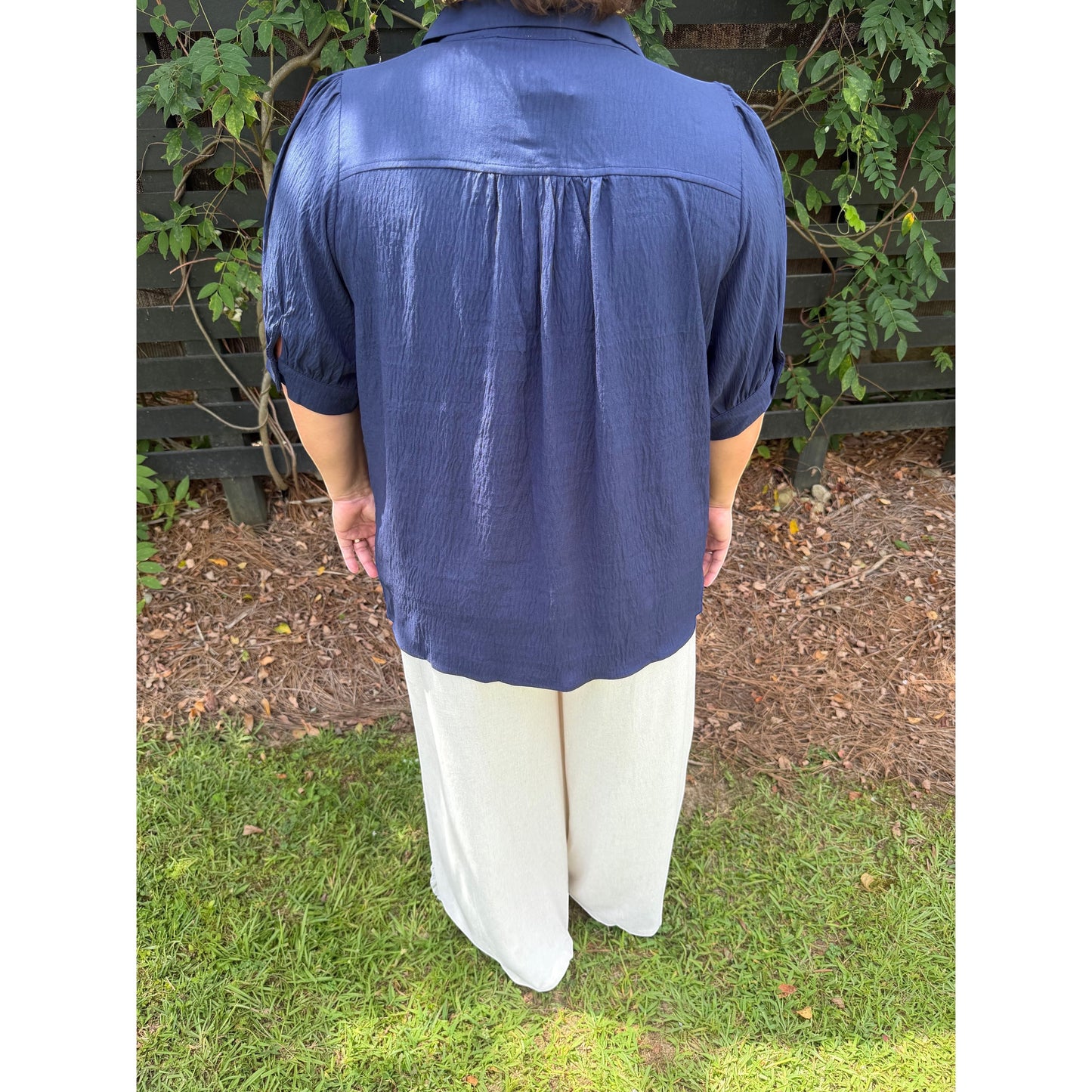 Annie Ks Boutique navy blouse with puff sleeves and back yoke detail worn with cream trousers in an outdoor setting