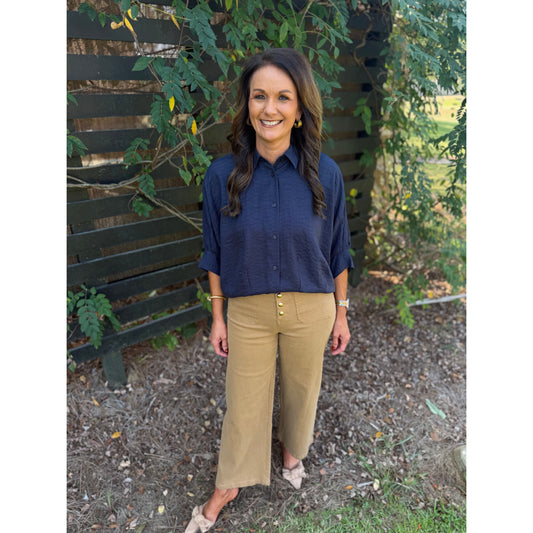 Annie Ks Boutique navy textured short sleeve blouse with a button-front, worn by a model with tan cropped trousers.