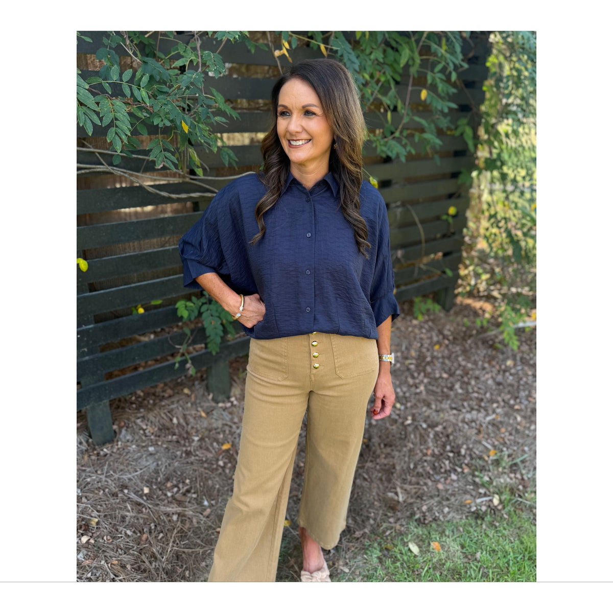 Annie Ks Boutique navy textured short sleeve blouse with a collar and dolman sleeves worn with tan pants outdoors