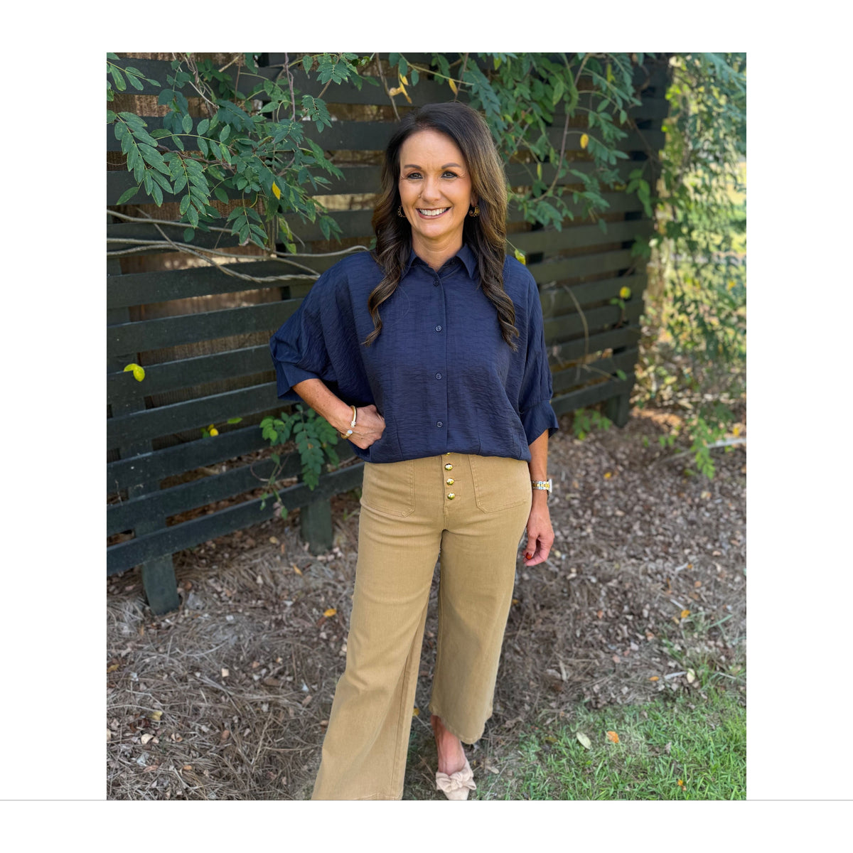 Annie Ks Boutique navy textured short sleeve blouse with a collar and button front, styled with tan trousers.