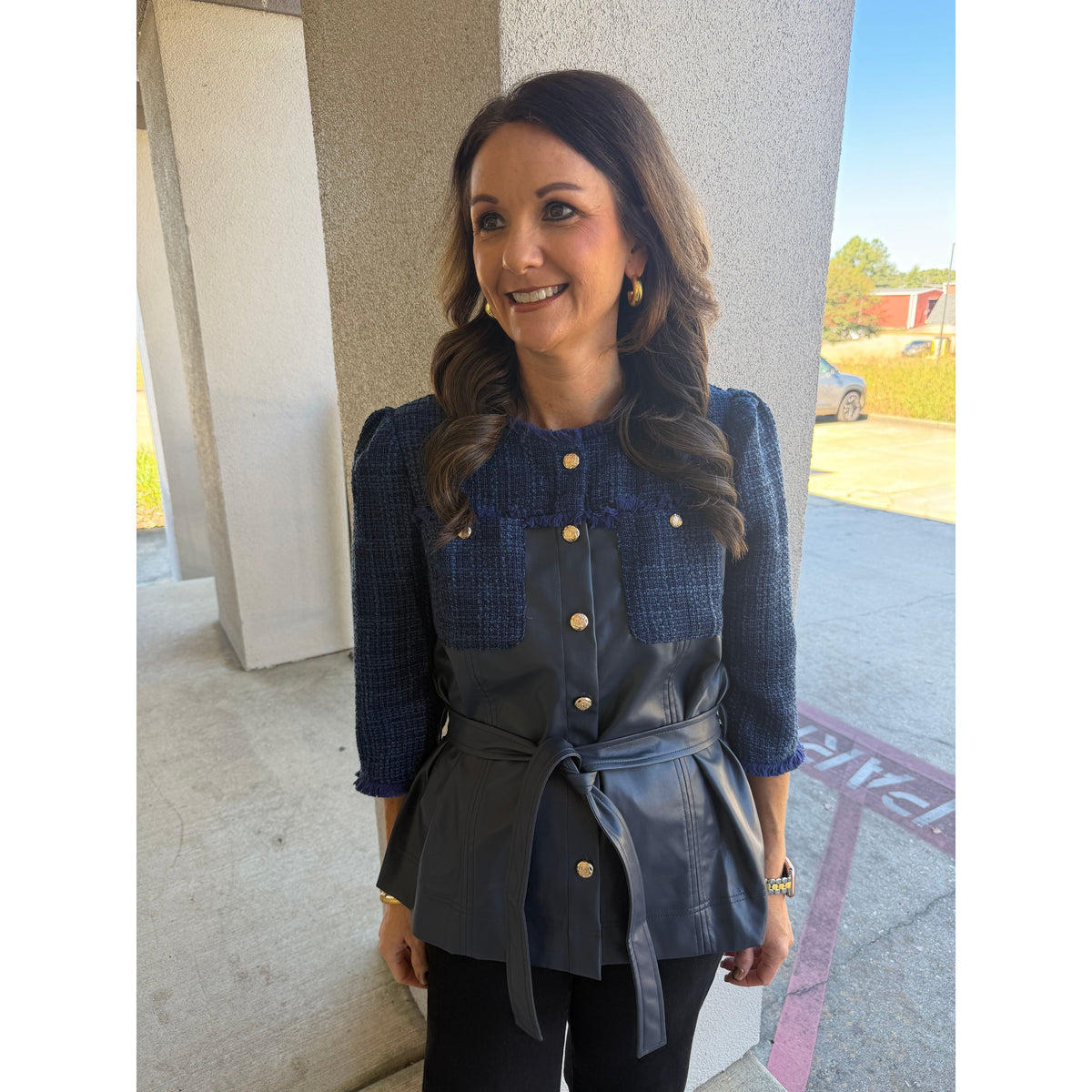 Annie Ks Boutique navy tweed and faux leather belted jacket with fringe trim and gold buttons worn by a smiling woman