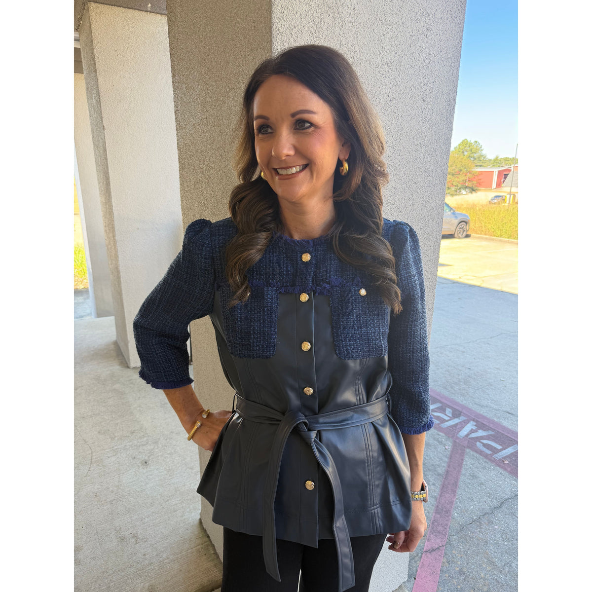 Annie Ks Boutique navy tweed and faux leather belted jacket with fringe trim and gold buttons worn by a smiling woman