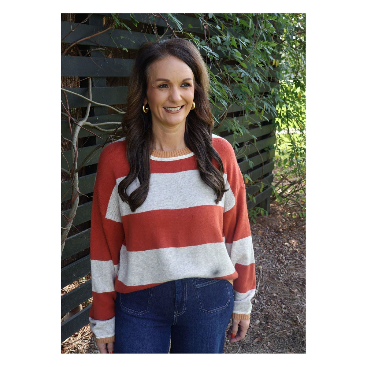 Annie Ks Boutique model wearing an oatmeal and brick red striped knit sweater with a crew neck and relaxed fit.