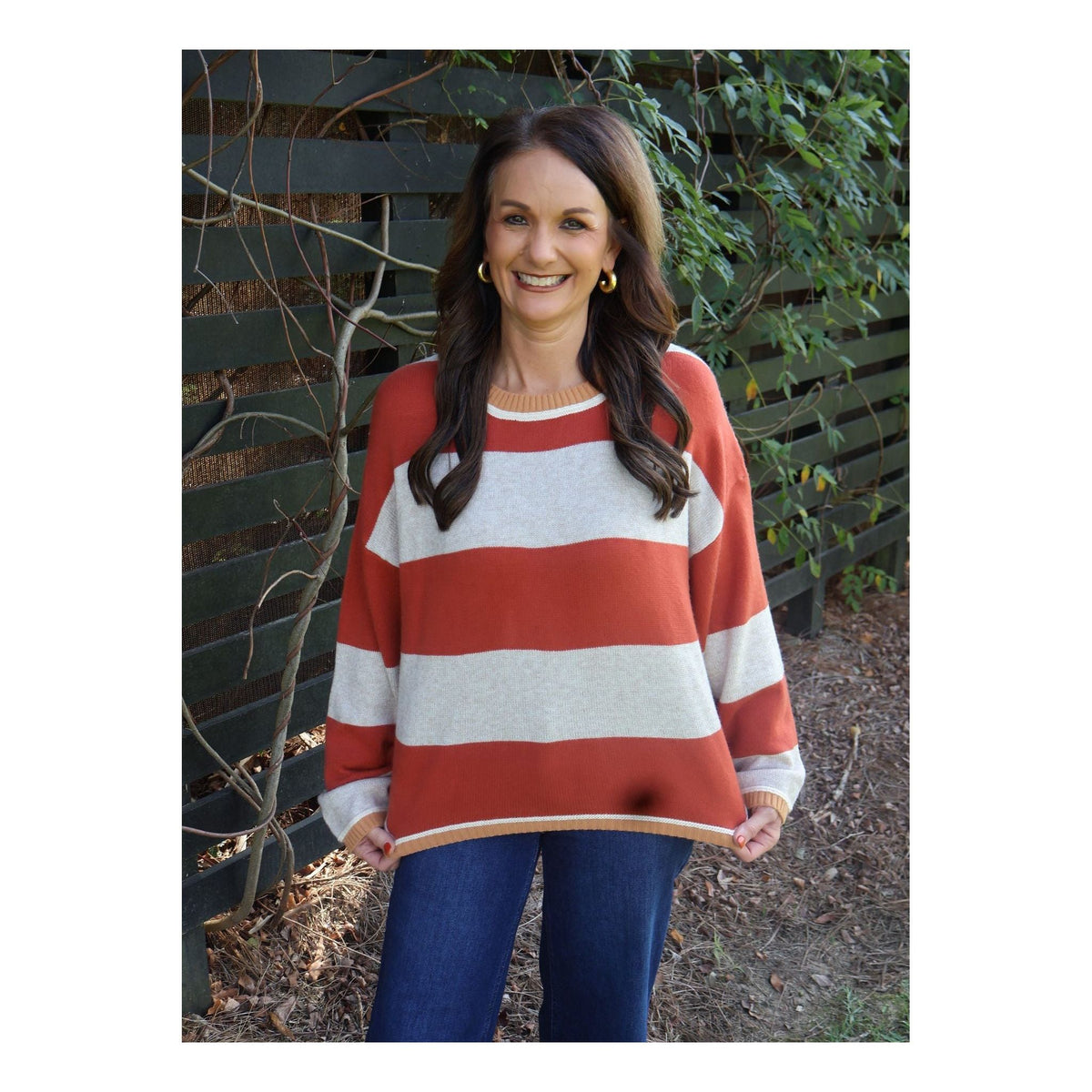 Annie Ks Boutique oatmeal and brick red striped knit sweater with a relaxed fit worn by a smiling woman outdoors.
