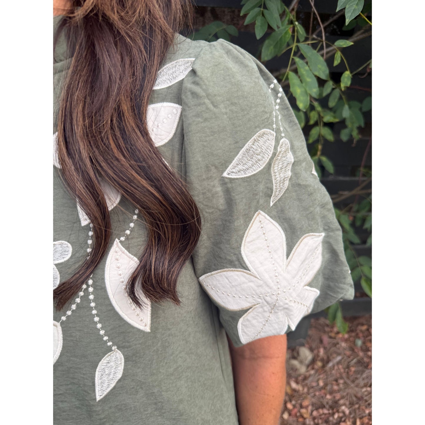 Annie Ks Boutique olive mini dress with white floral applique embroidery and puff sleeves on a woman