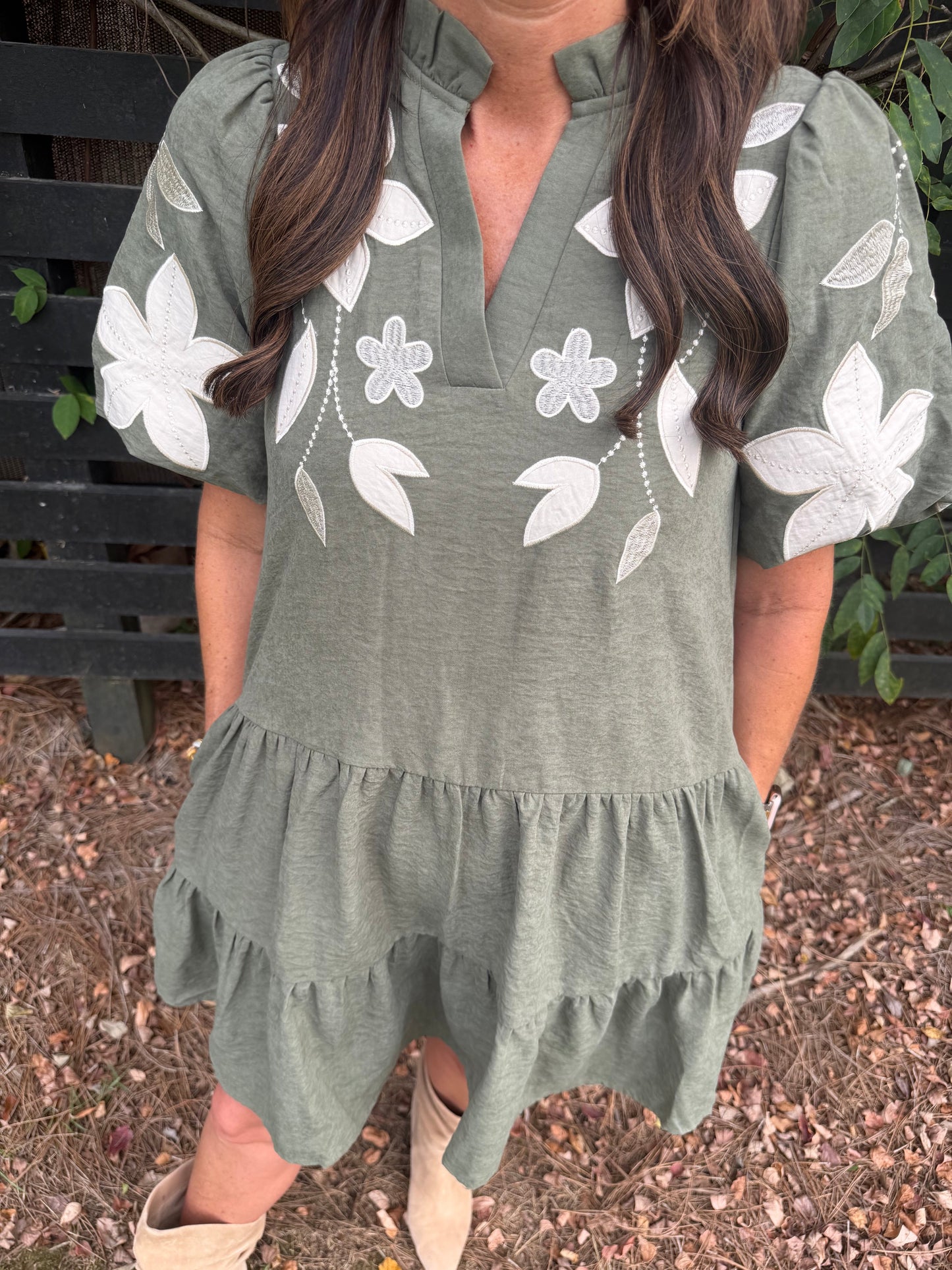Annie Ks Boutique olive mini dress with white floral applique, split neckline, and puff sleeves on a woman.