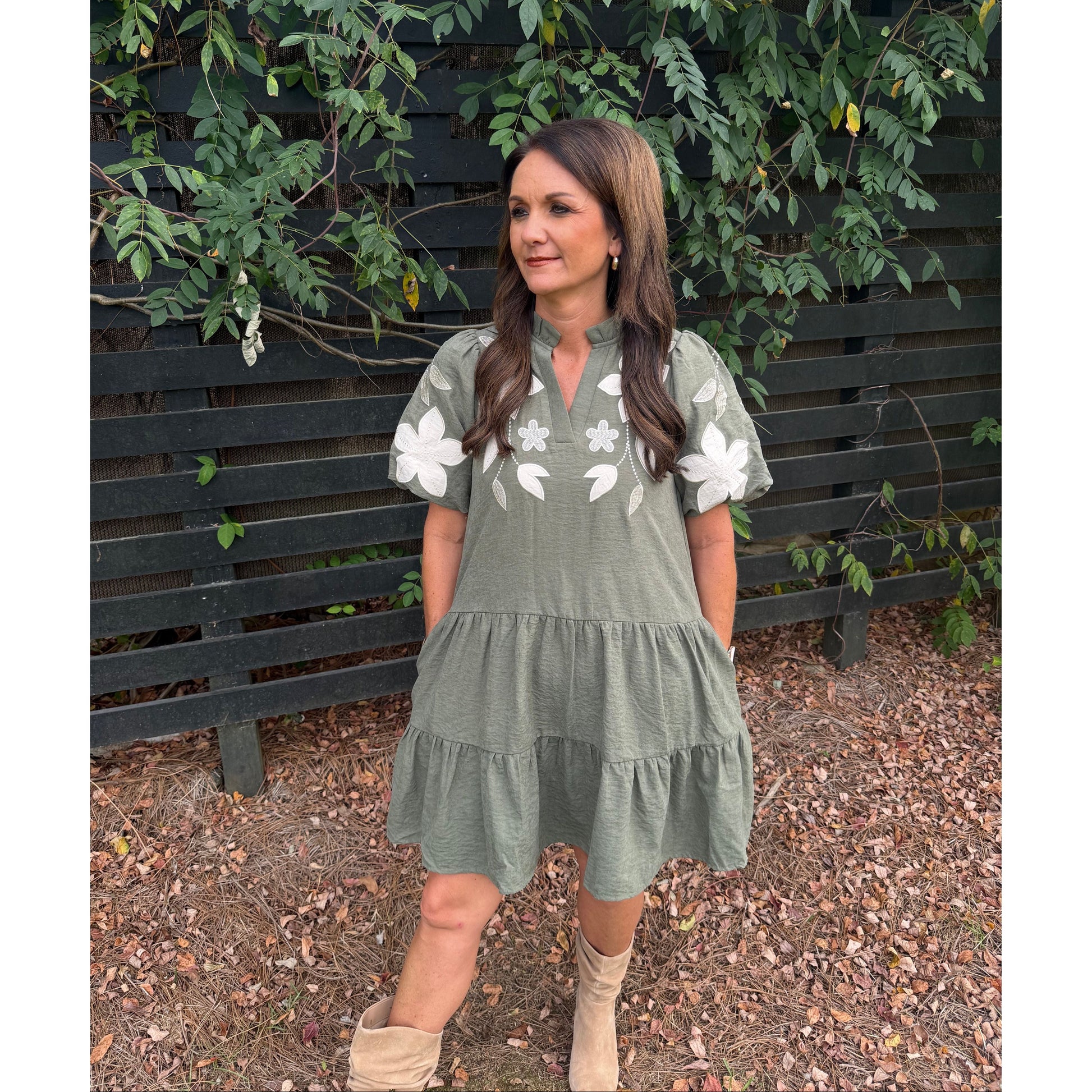Annie Ks Boutique olive tiered mini dress with white floral applique, puff sleeves, and split neckline on a woman.