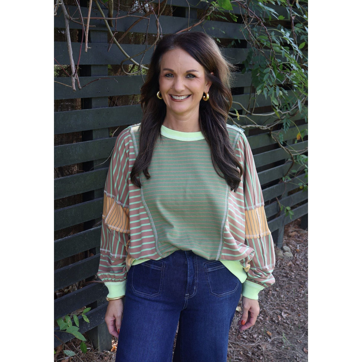 Annie Ks Boutique model wearing a loose fit olive and latte mixed stripe top with long sleeves and ribbed trim