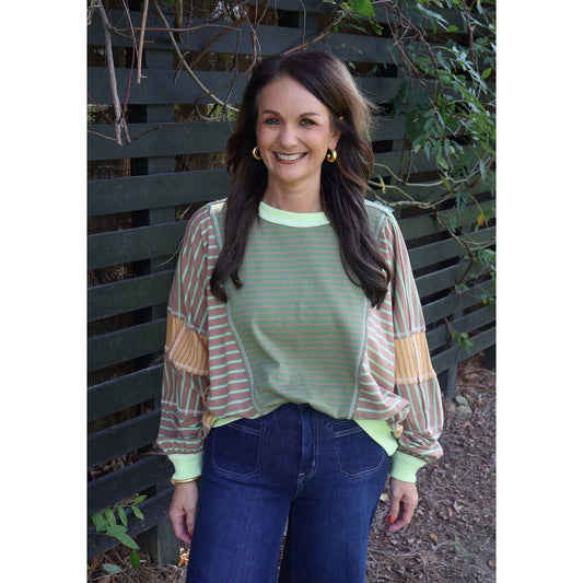 Annie Ks Boutique model wearing a loose fit olive and latte mixed stripe top with long sleeves and ribbed trim