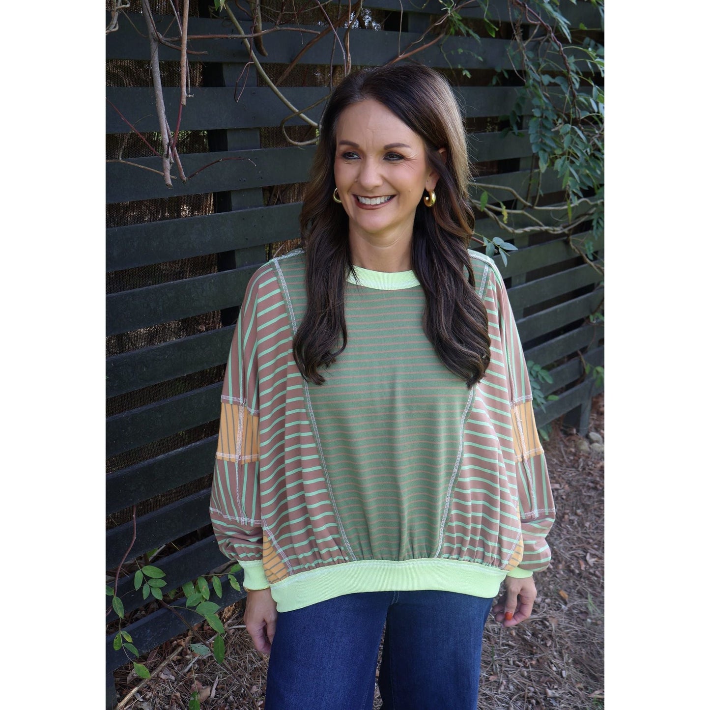 Annie Ks Boutique loose fit top featuring olive and latte mixed stripes with lime green trim worn by a smiling woman