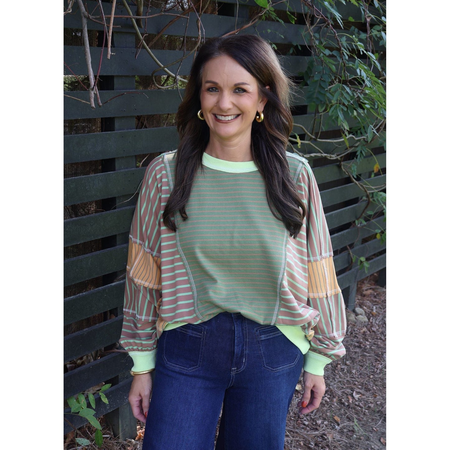 Annie Ks Boutique loose fit top featuring olive and latte mixed stripes, worn by a woman with dark hair outdoors.