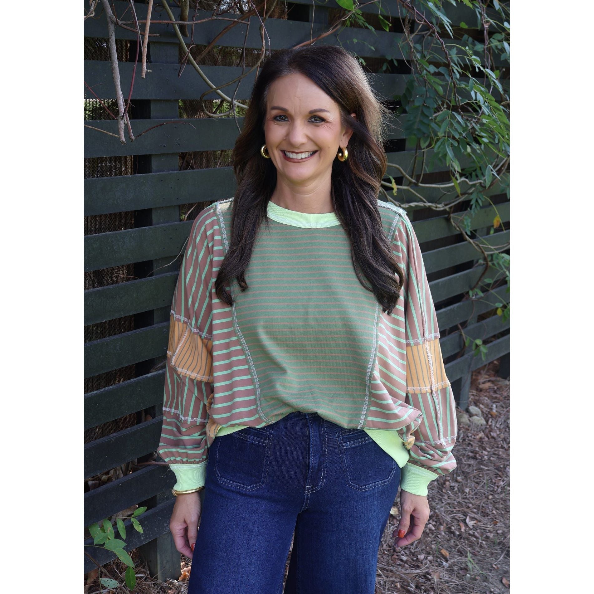 Annie Ks Boutique loose fit top featuring olive and latte mixed stripes, worn by a woman with dark hair outdoors.