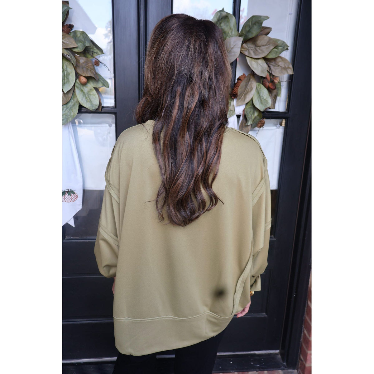 Annie Ks Boutique olive green oversized French terry sweatshirt with raw-edge detailing, viewed from the back.