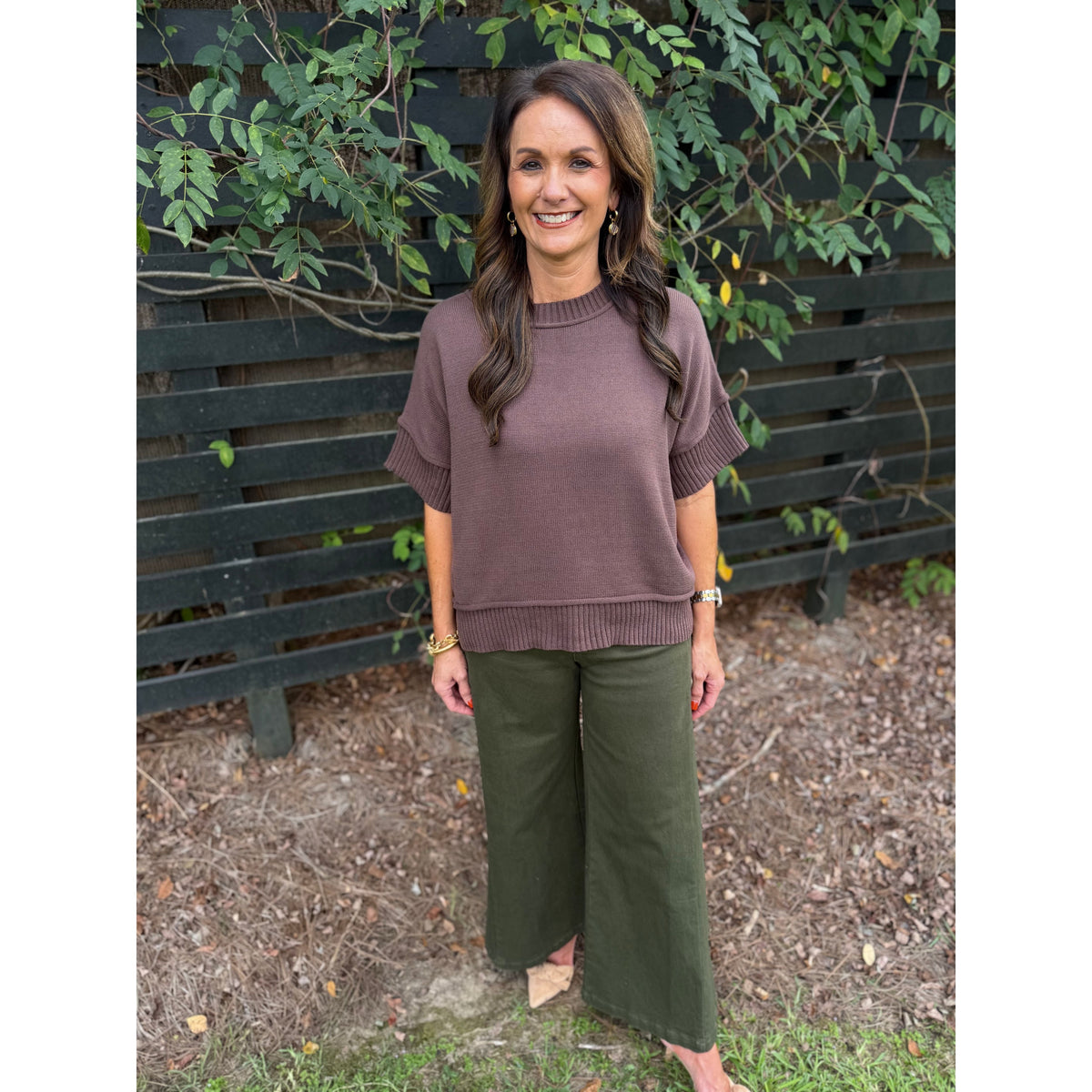 Annie Ks Boutique olive wide-leg trousers paired with a brown knit top on a smiling woman standing outdoors