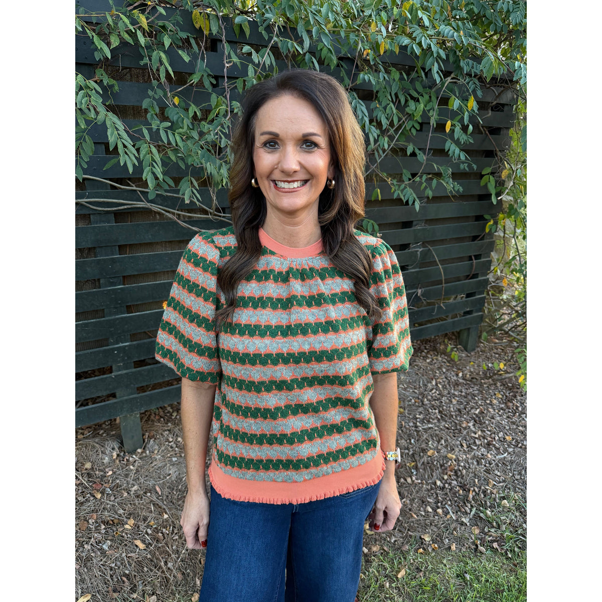 Annie Ks Boutique orange and green geometric stripe knit top with bubble sleeves worn by a woman outdoors.