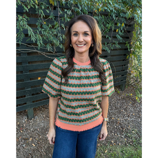 Annie Ks Boutique orange and green geometric stripe knit top with short bubble sleeves and ribbed trim on a woman