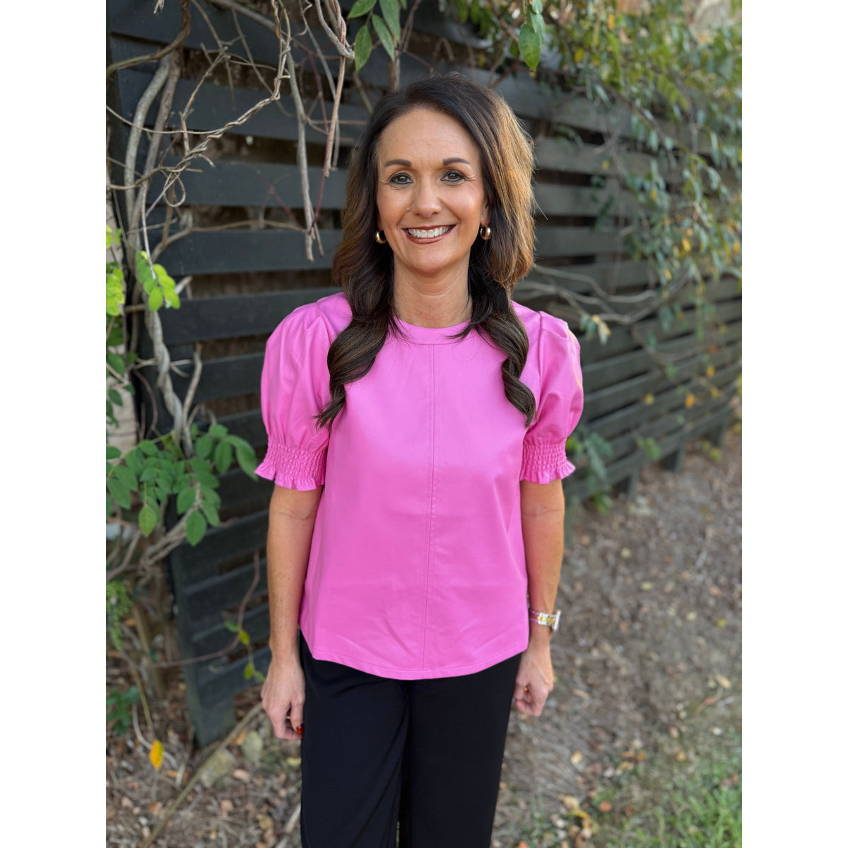 Annie Ks Boutique THML pink faux leather top with short puff sleeves and crew neck worn by a smiling woman outdoors.