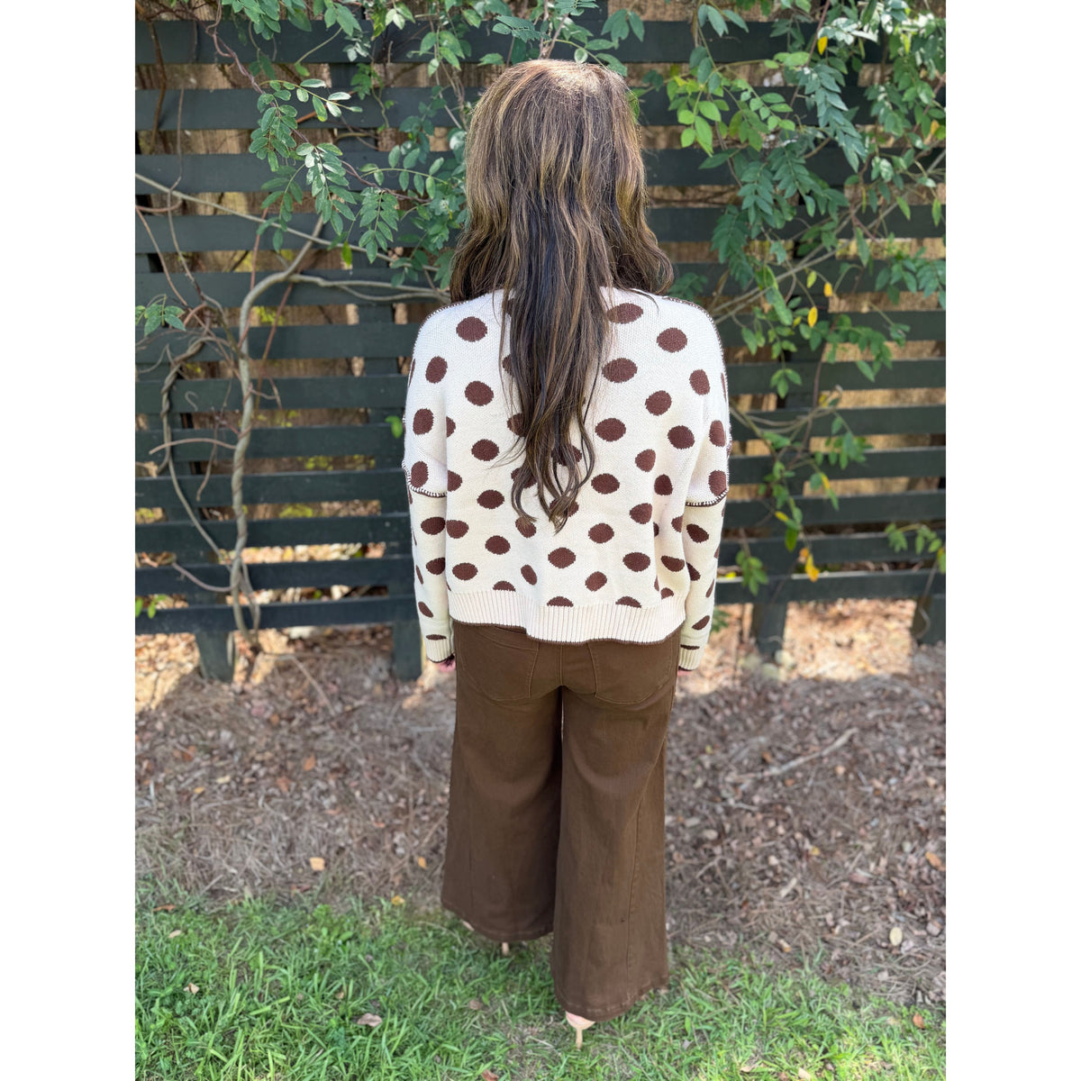 Annie Ks Boutique oatmeal and coffee polka dot loose fit knit sweater worn with brown trousers, back view