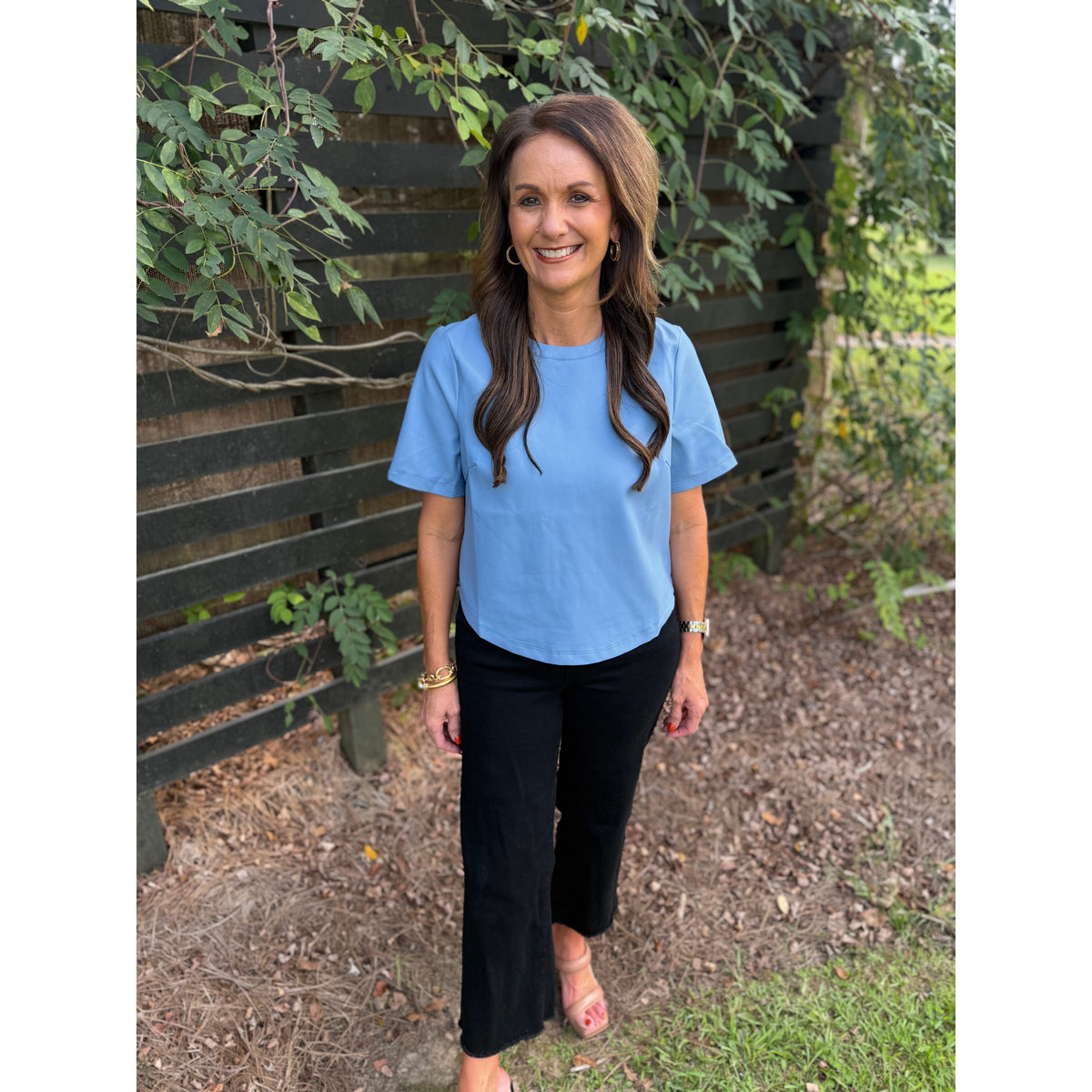 Annie Ks Boutique powder blue faux leather short-sleeve top worn by a woman with black trousers in an outdoor setting