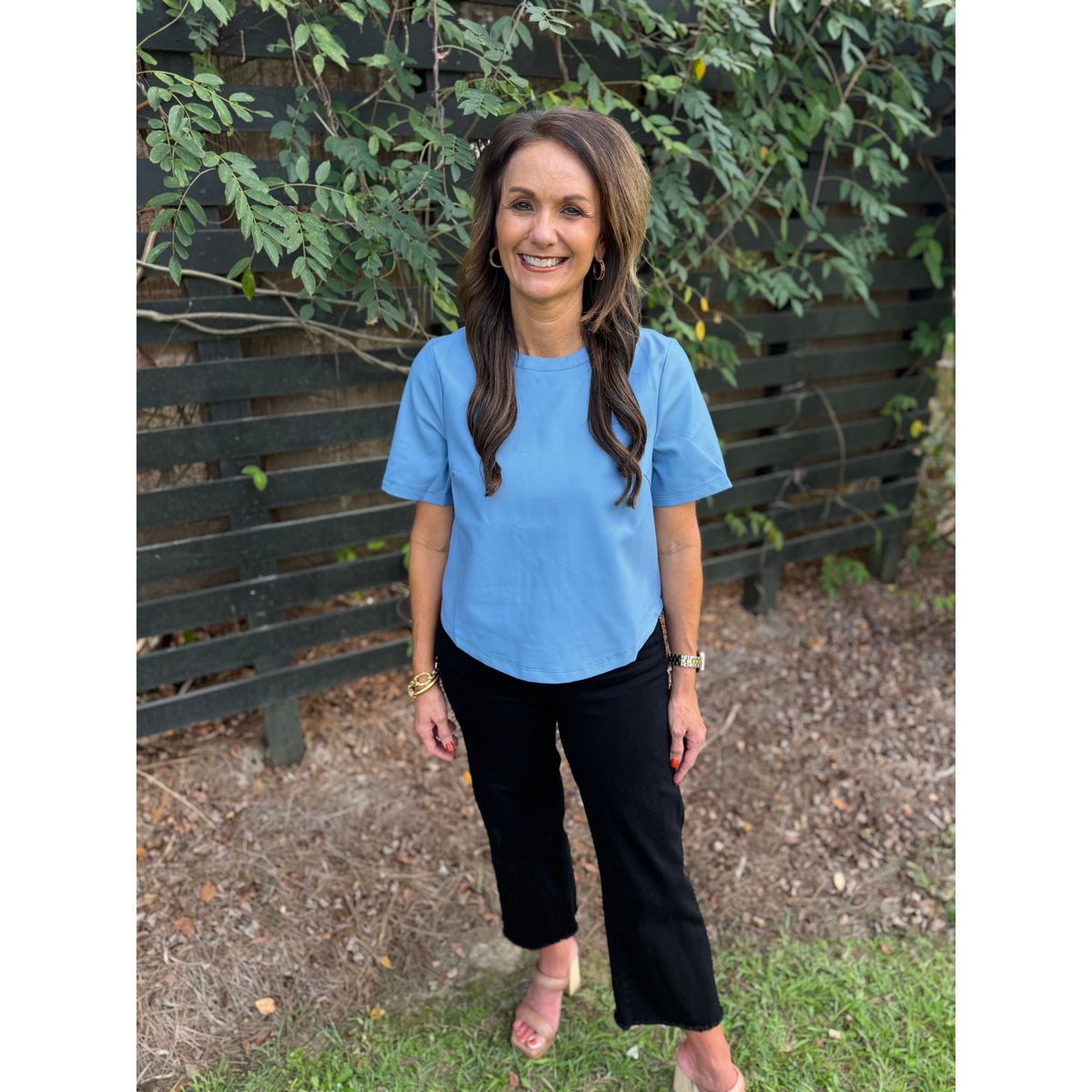 Annie Ks Boutique powder blue short-sleeve faux leather top worn by a woman with black trousers and block heels