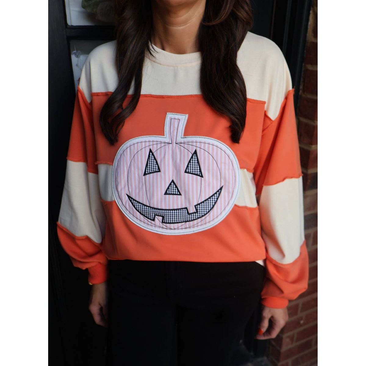 Annie Ks Boutique orange and cream color-block pullover featuring a large patchwork pumpkin appliqué graphic