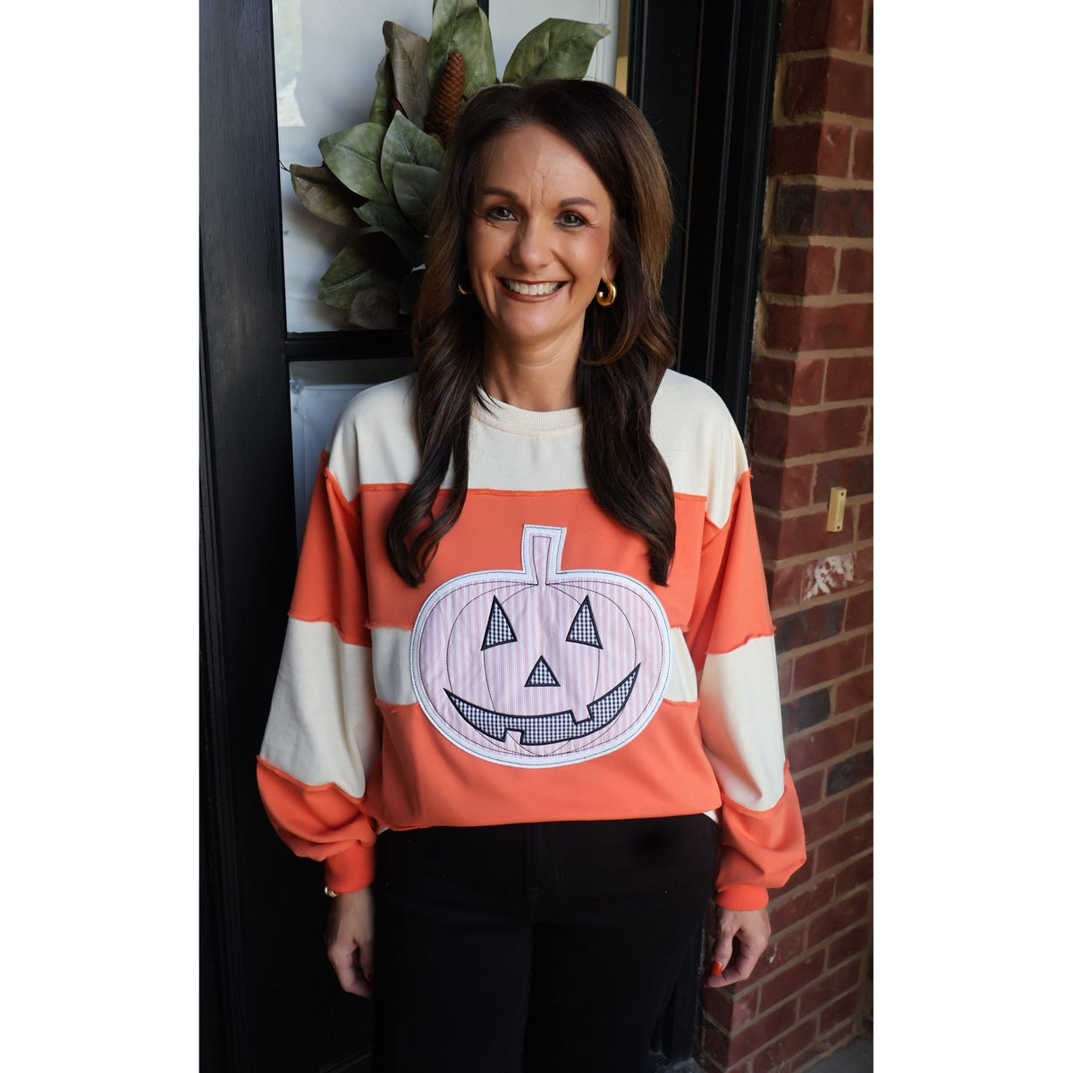 Annie Ks Boutique orange and cream color-block pullover with a large pumpkin appliqué graphic and ribbed cuffs.