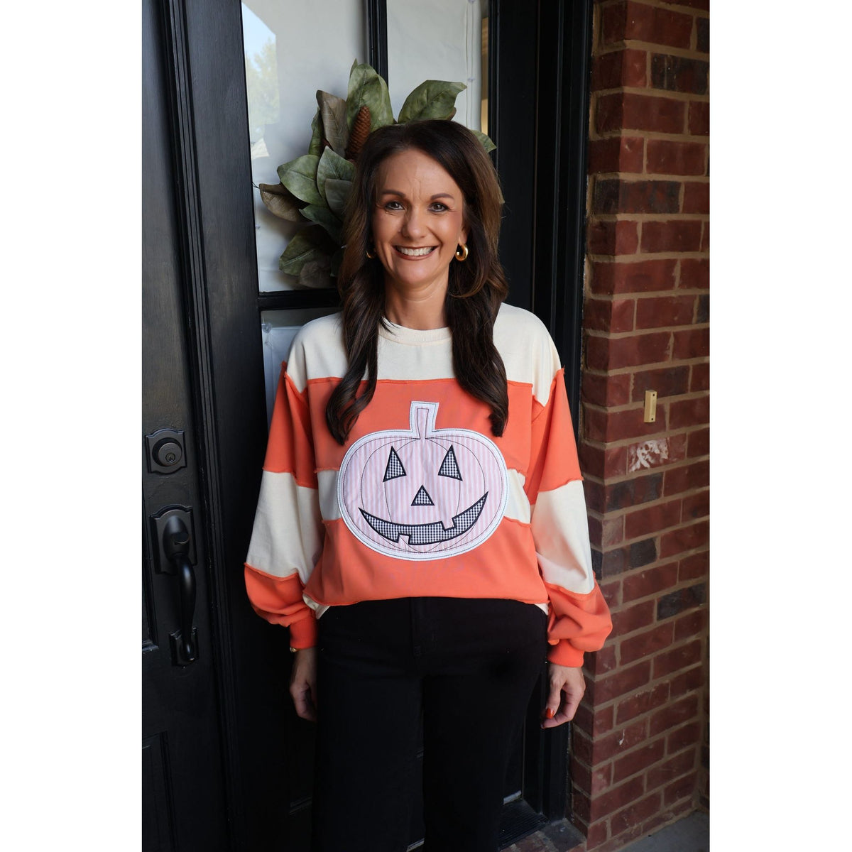Annie Ks Boutique orange and cream color-block pullover with a large pumpkin appliqué for fall and Halloween style.