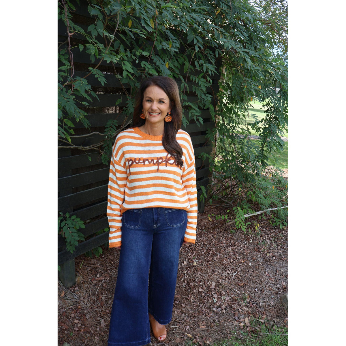 Annie Ks Boutique orange and ivory striped knit sweater with pumpkin script applique worn with dark denim jeans