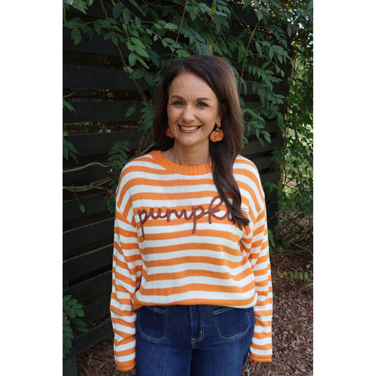 Annie Ks Boutique orange and ivory striped knit sweater with pumpkin script applique worn by a smiling woman
