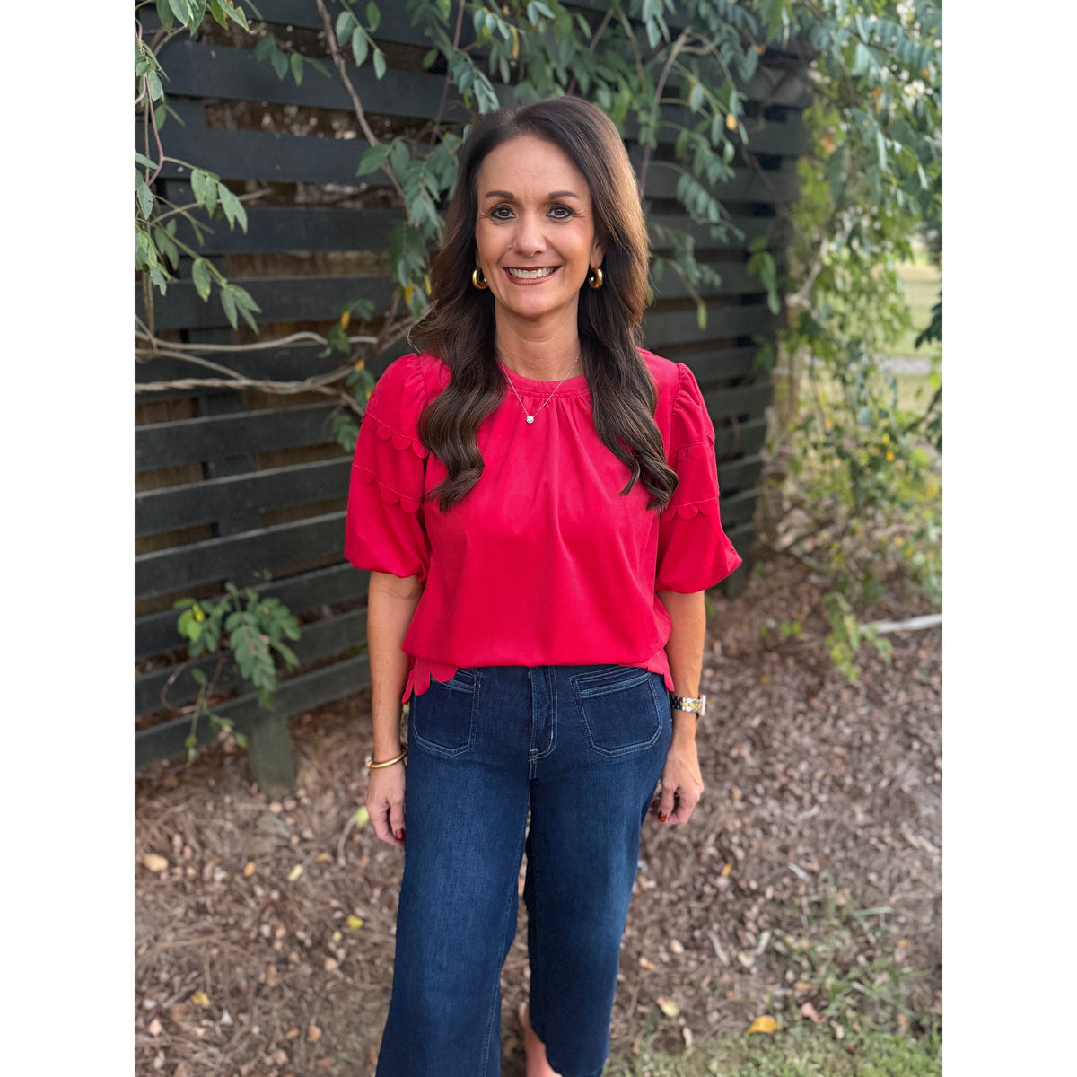 Annie Ks Boutique red corduroy top with bubble sleeves and scalloped hem worn by a woman with dark wavy hair