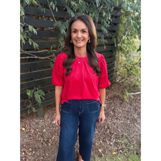 Annie Ks Boutique red corduroy top with bubble sleeves and scalloped hem worn by a woman with dark wavy hair