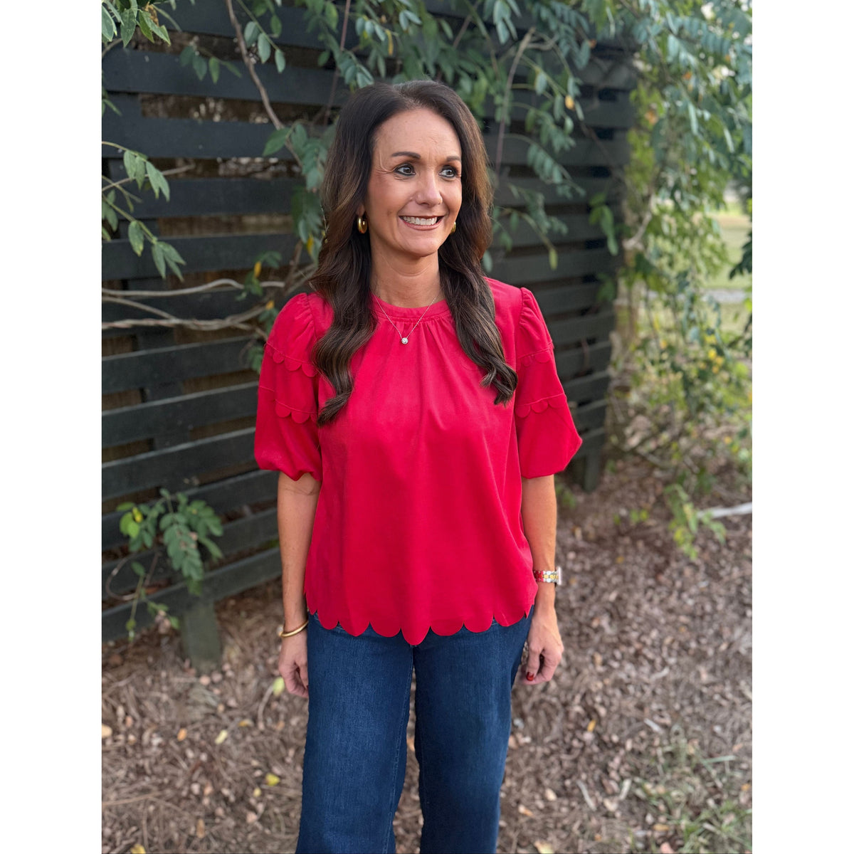 Annie Ks Boutique red corduroy top with bubble sleeves and scalloped hemline worn by a woman with dark wavy hair