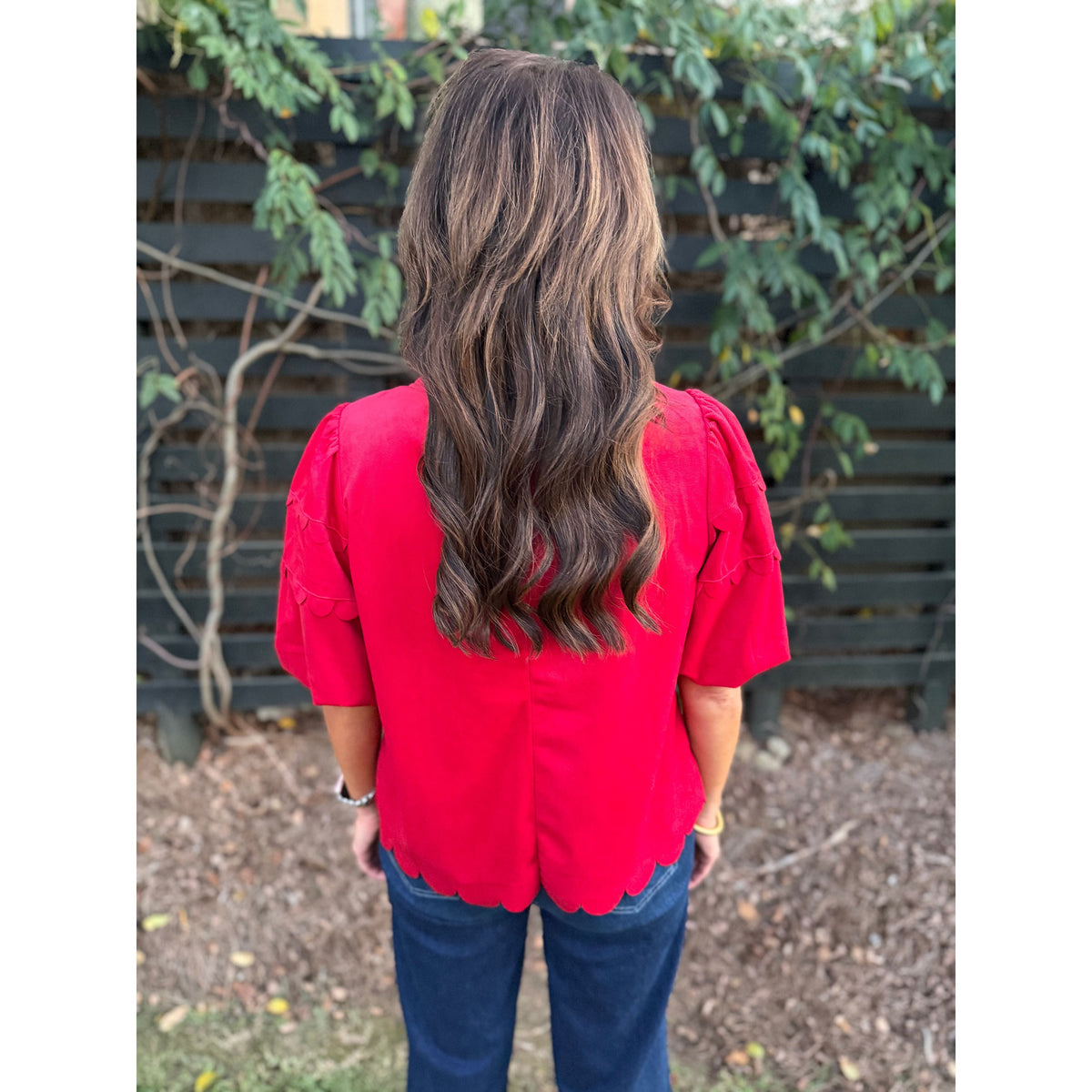 Annie Ks Boutique red corduroy top with bubble sleeves and scalloped hemline worn by a woman from the back view