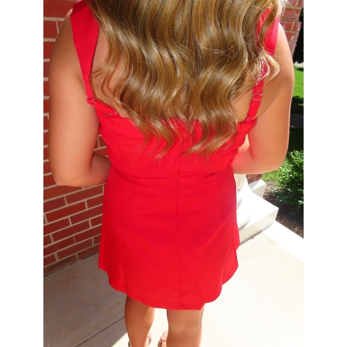 Back view of a woman wearing an Annie Ks Boutique red mini skort romper with wide straps and an invisible back zipper.