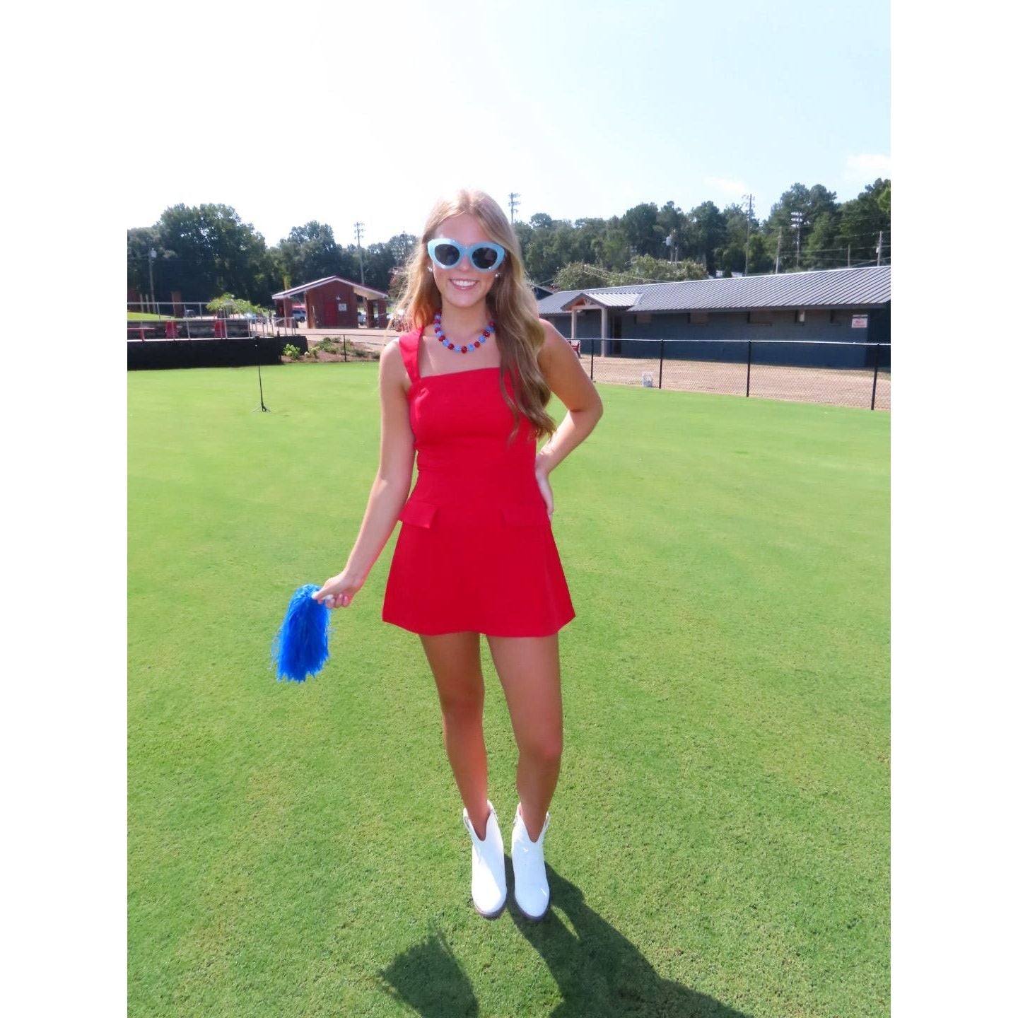 Annie Ks Boutique red mini skort romper with straight neckline and faux flap pockets worn by a woman on a grassy field
