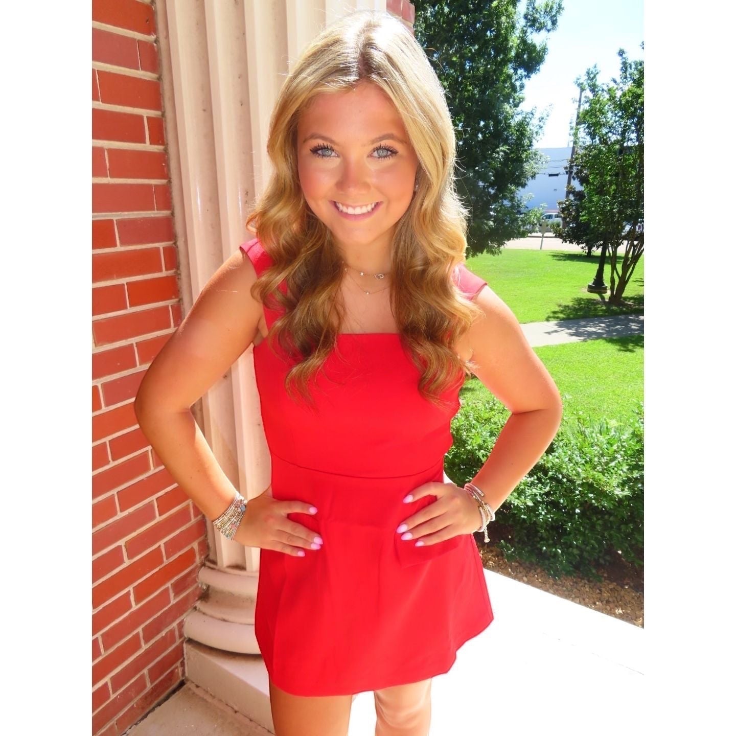 Annie Ks Boutique red mini skort romper with straight neckline and wide straps worn by a smiling blonde model