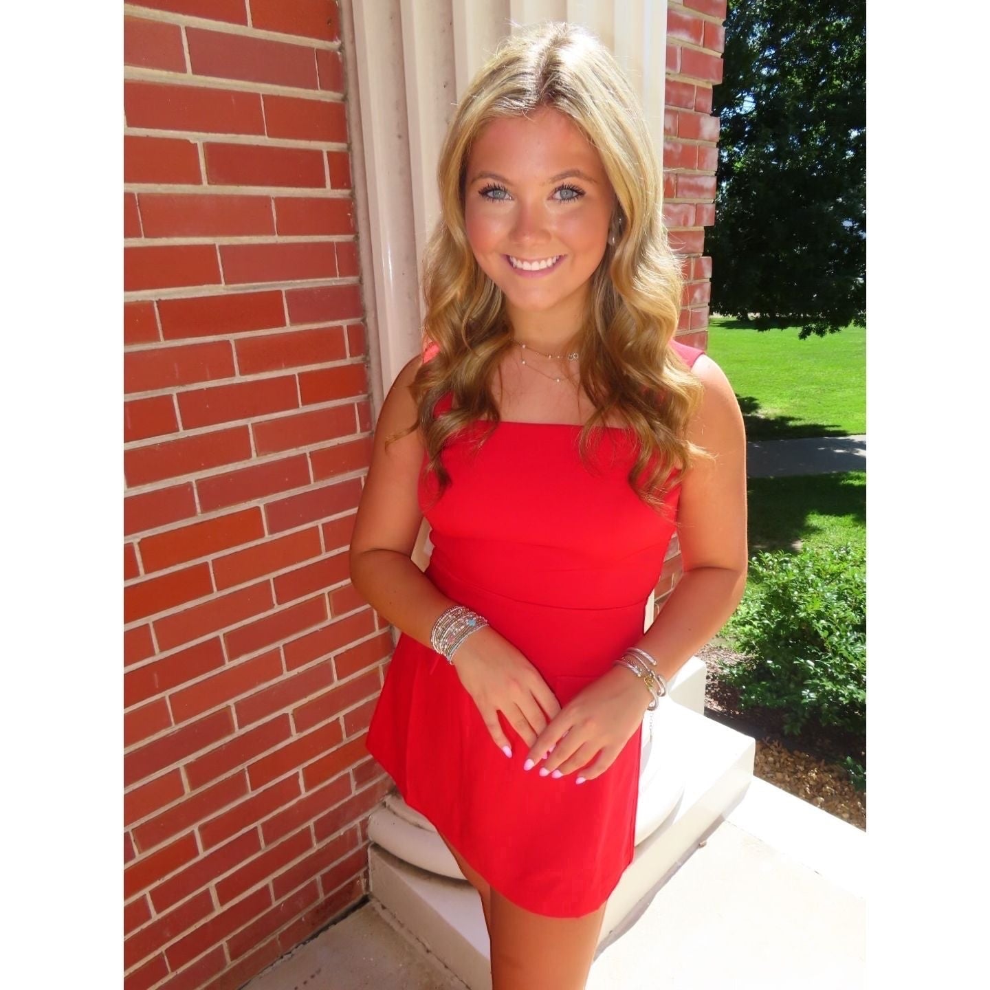 Annie Ks Boutique red mini skort romper with a straight neckline and wide straps worn by a smiling blonde model