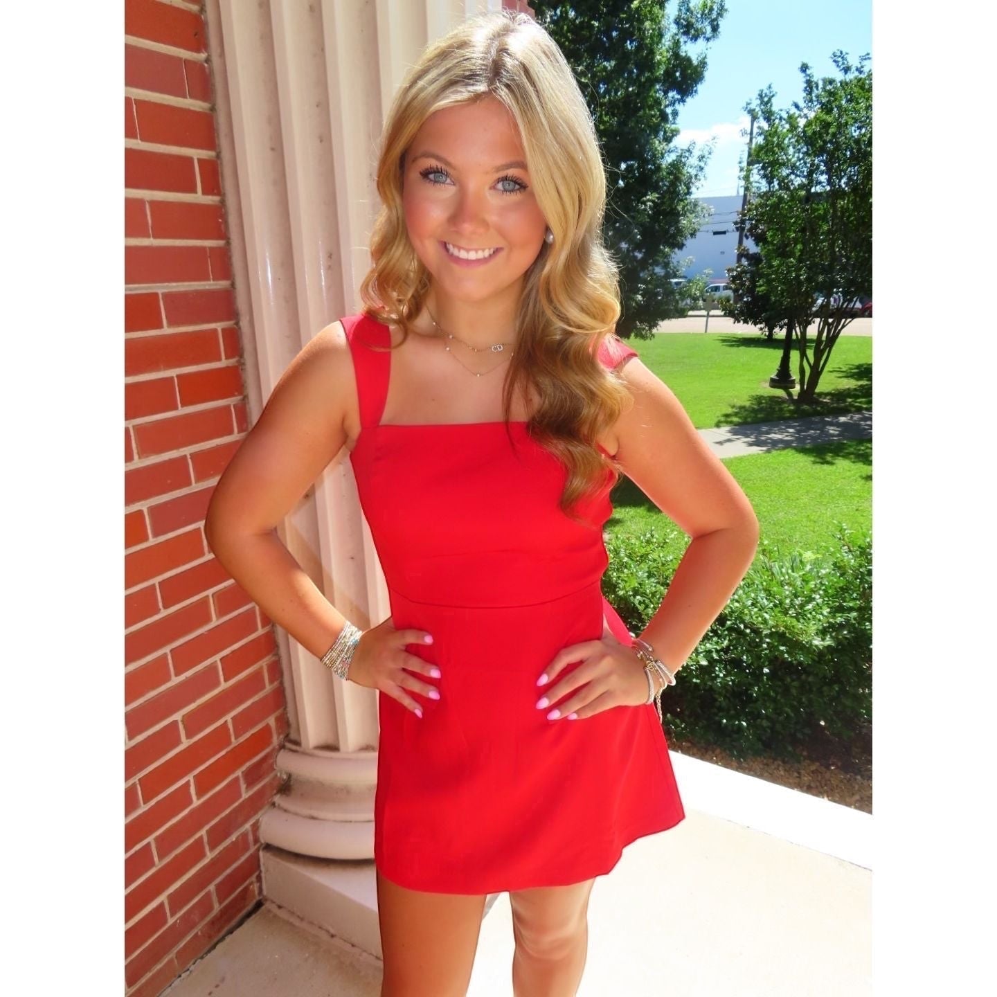 Annie Ks Boutique red mini skort romper with a straight neckline and wide straps worn by a smiling blonde model.