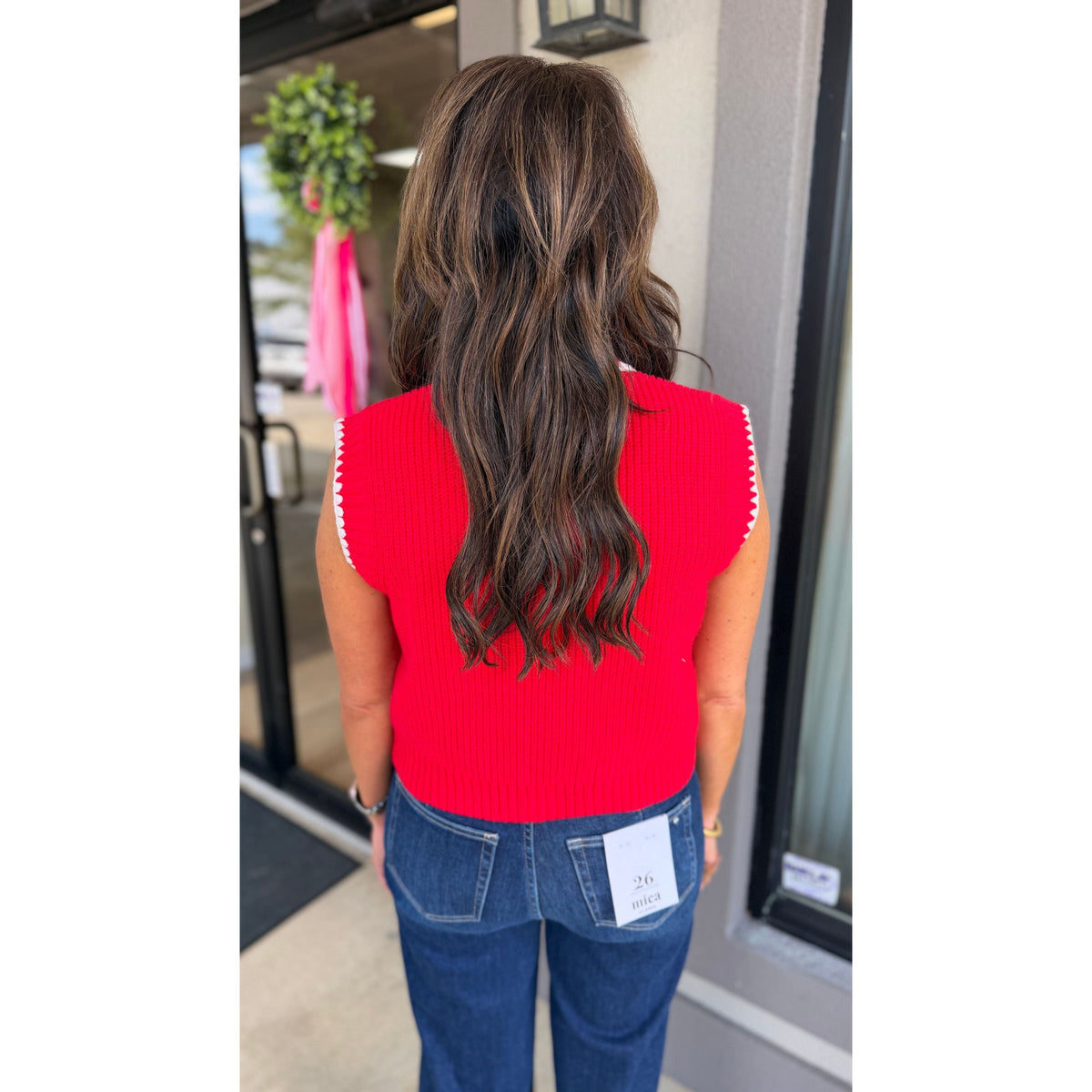 Annie Ks Boutique red sweater vest with white blanket stitching worn by a woman with long wavy brown hair