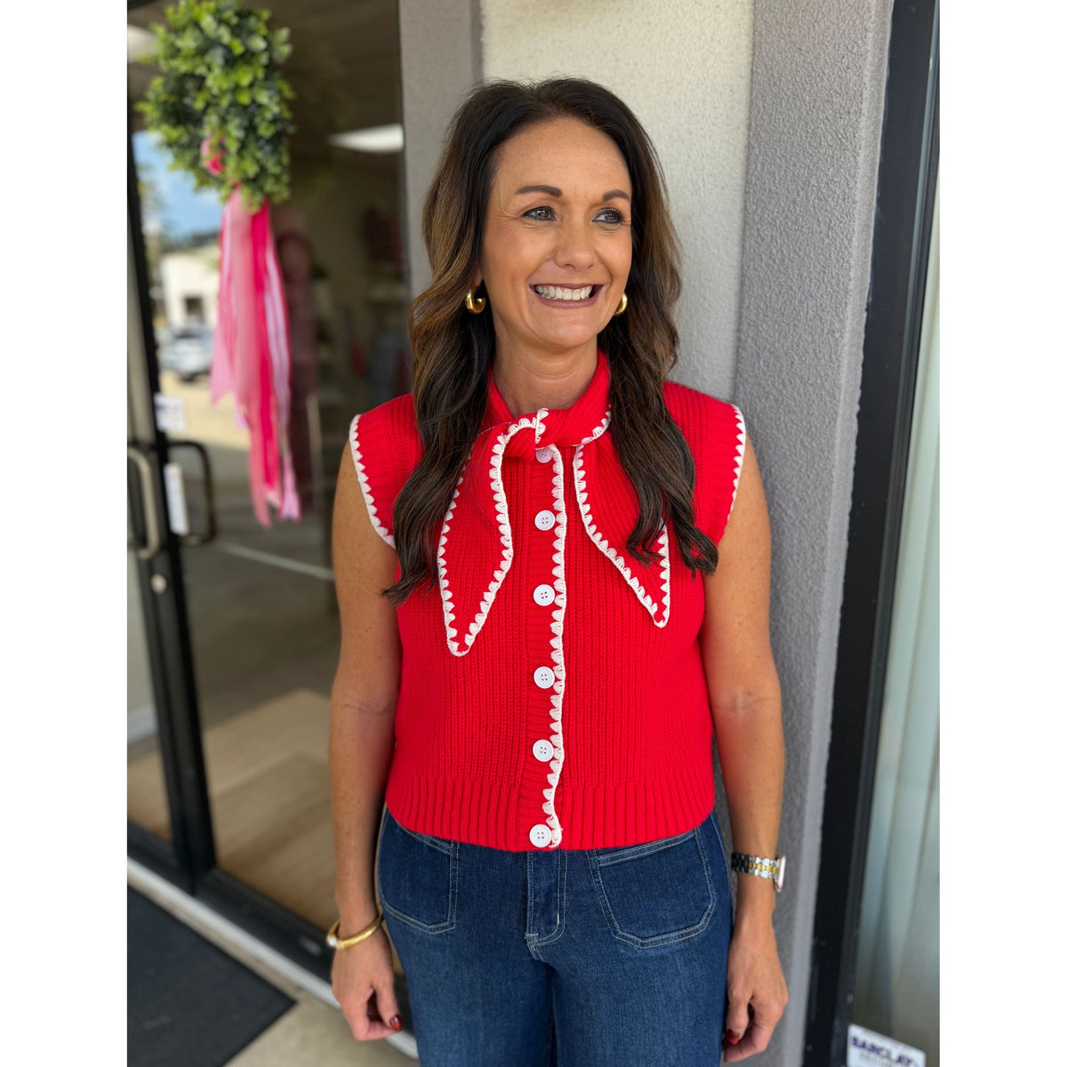 Annie Ks Boutique red and white sweater vest with button front, tie neck, and contrast blanket stitching details.