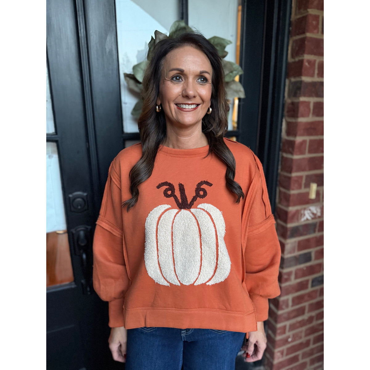 Woman wearing an Annie Ks Boutique vintage rust pullover with a plush white pumpkin patch and drop shoulders.